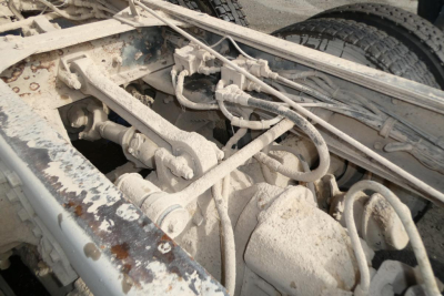 Truck chassis with exposed mechanical linkages and hoses in a Peterbilt dump truck frame.