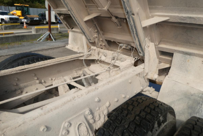 Peterbilt 357 dump truck chassis and rear frame with hydraulic lift, viewed from side; beige/gray paint, exposed bolts, dual rear wheels, and undercarriage.