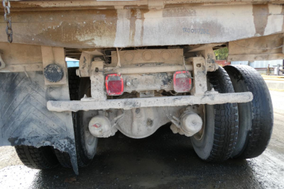 Peterbilt 357 dump truck rear undercarriage showing dual rear wheels, hitch assembly, and mudflap with dirt and grime.