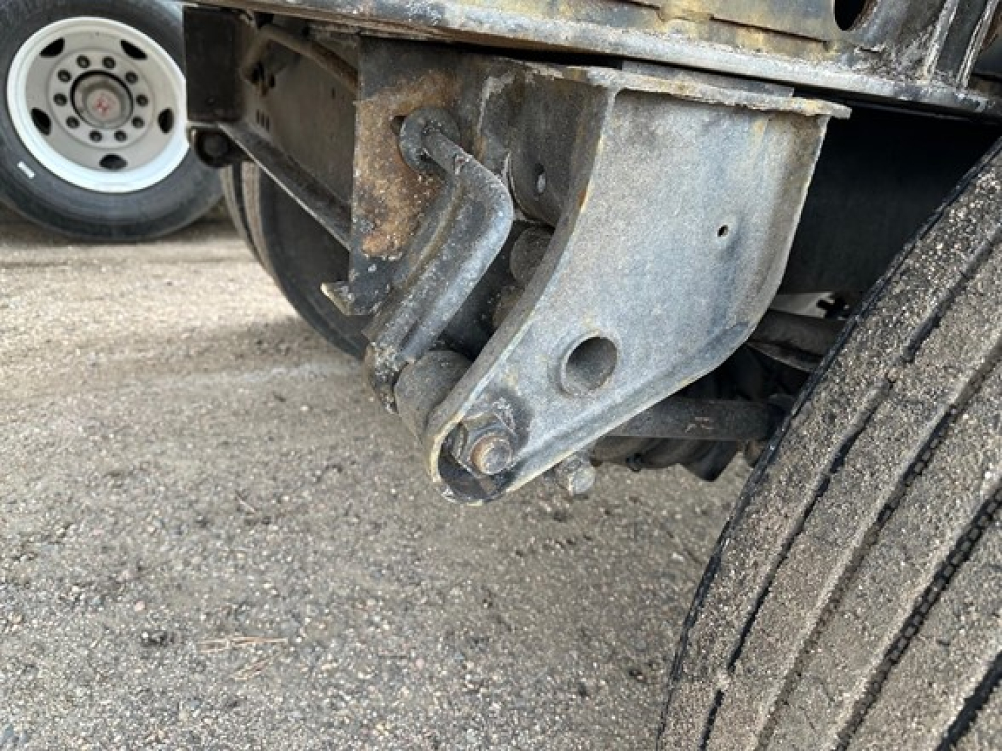 Flatbed trailer hitch and rear suspension hardware visible under 2018 Fontaine Velocity steel flatbed trailer showing suspension bracket and axles.