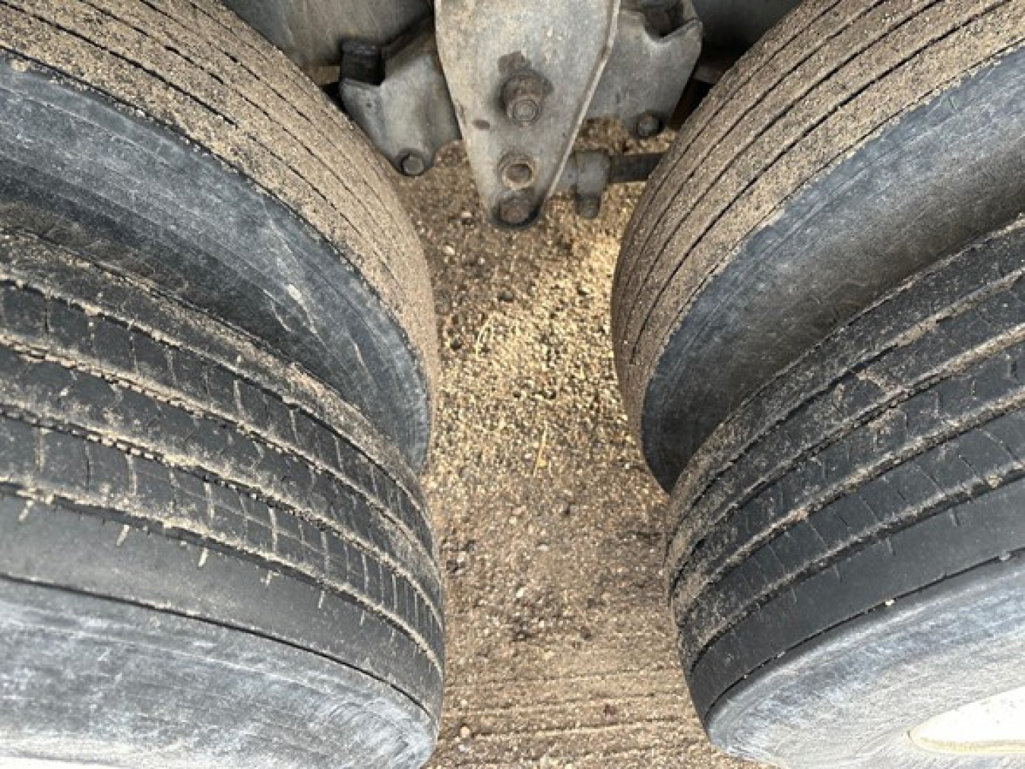Flatbed trailer axle with dual rear wheels showing tread and dirt buildup; part of Fontaine Velocity Steel Flatbed trailer (underbody view).