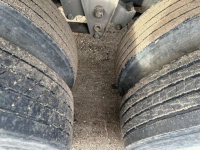 Trailer landing gear and dual rear axles with tires in view; close-up of wheel hubs and frame of a Fontaine Velocity steel flatbed trailer.