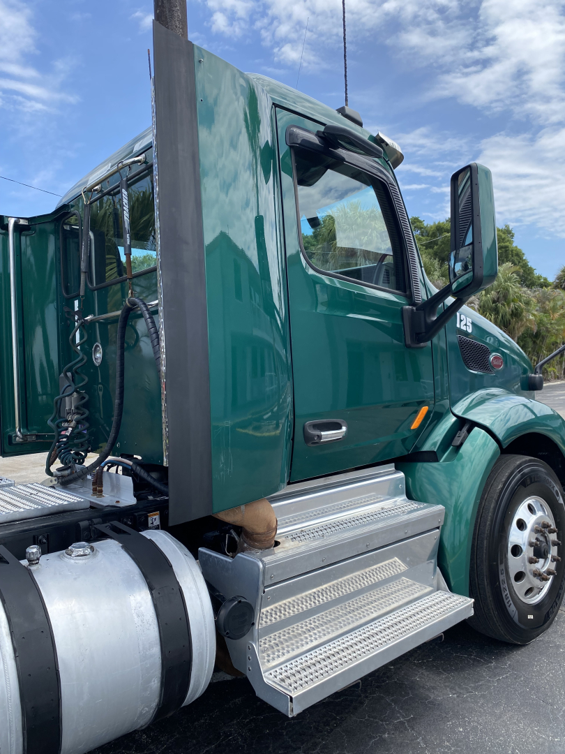 Peterbilt 579 day cab truck, green cab, side steps, fuel tank, and door mirror visible