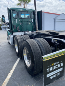 Peterbilt 579 day cab truck rear view showing dual rear axles and green cab.