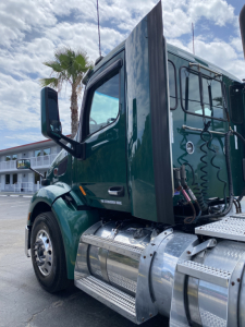 Peterbilt 579 day cab truck in green, side view focusing on chrome fuel tanks and step rungs, exterior mirrors, and bunk area.