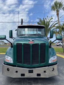Peterbilt 579 day cab front view showing green exterior, large black grille, chrome bumper, and side mirrors.