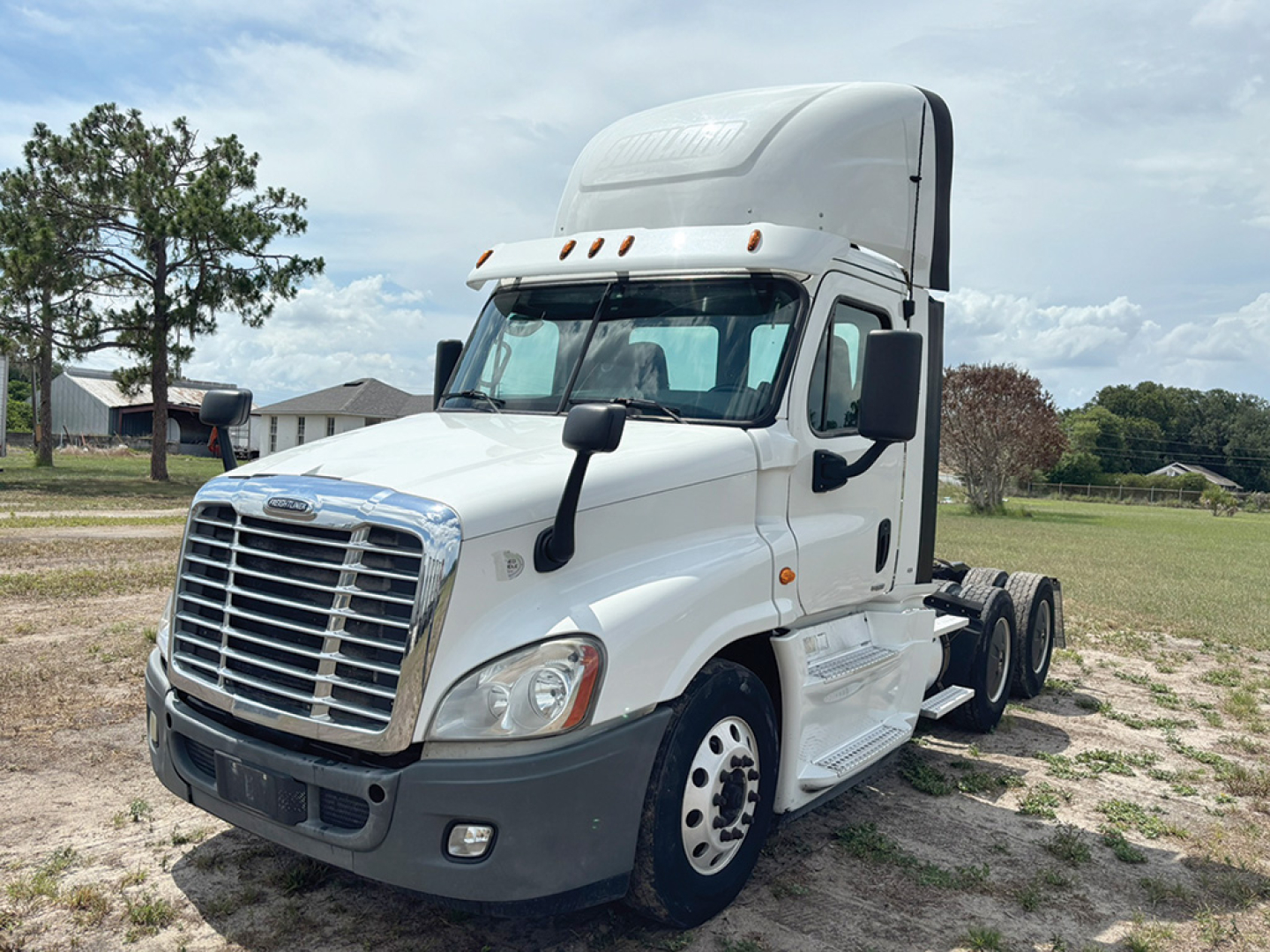 Truck cab side view showing Freightliner Cascadia Evolution with sleeper and white cab, front grille, headlights, and chassis behind the cab.