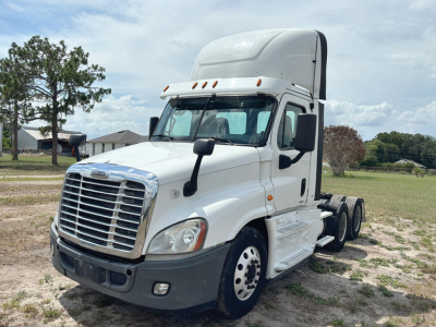 Truck cab side view showing Freightliner Cascadia Evolution with sleeper and white cab, front grille, headlights, and chassis behind the cab.