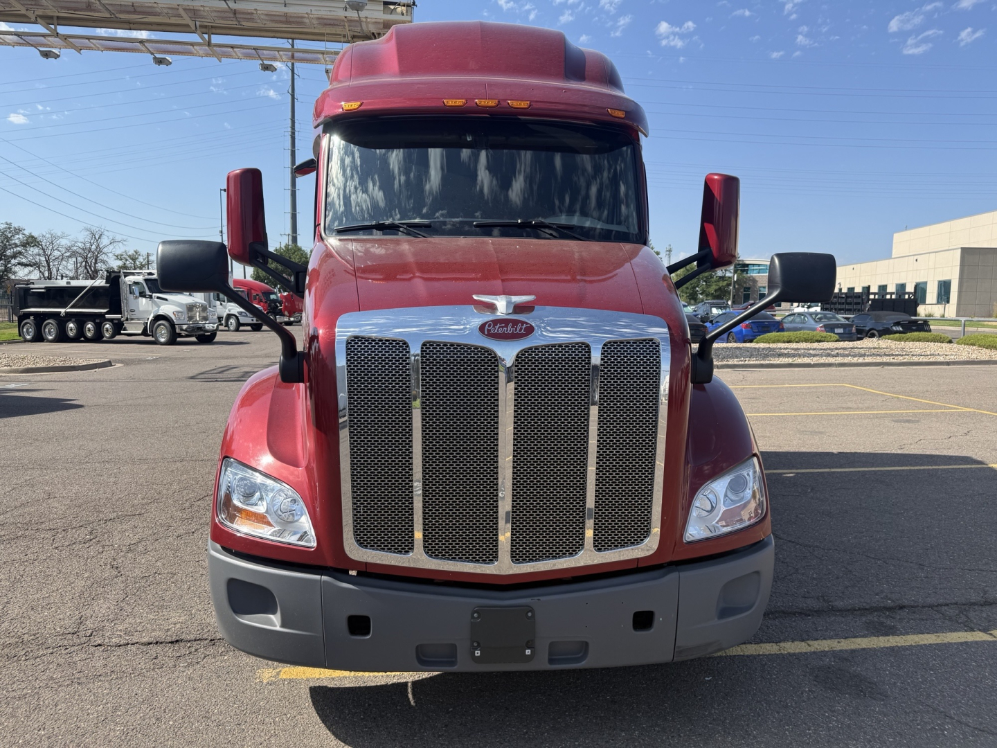 Peterbilt 579 front view showing large chrome grille and red cab with black mirrors.