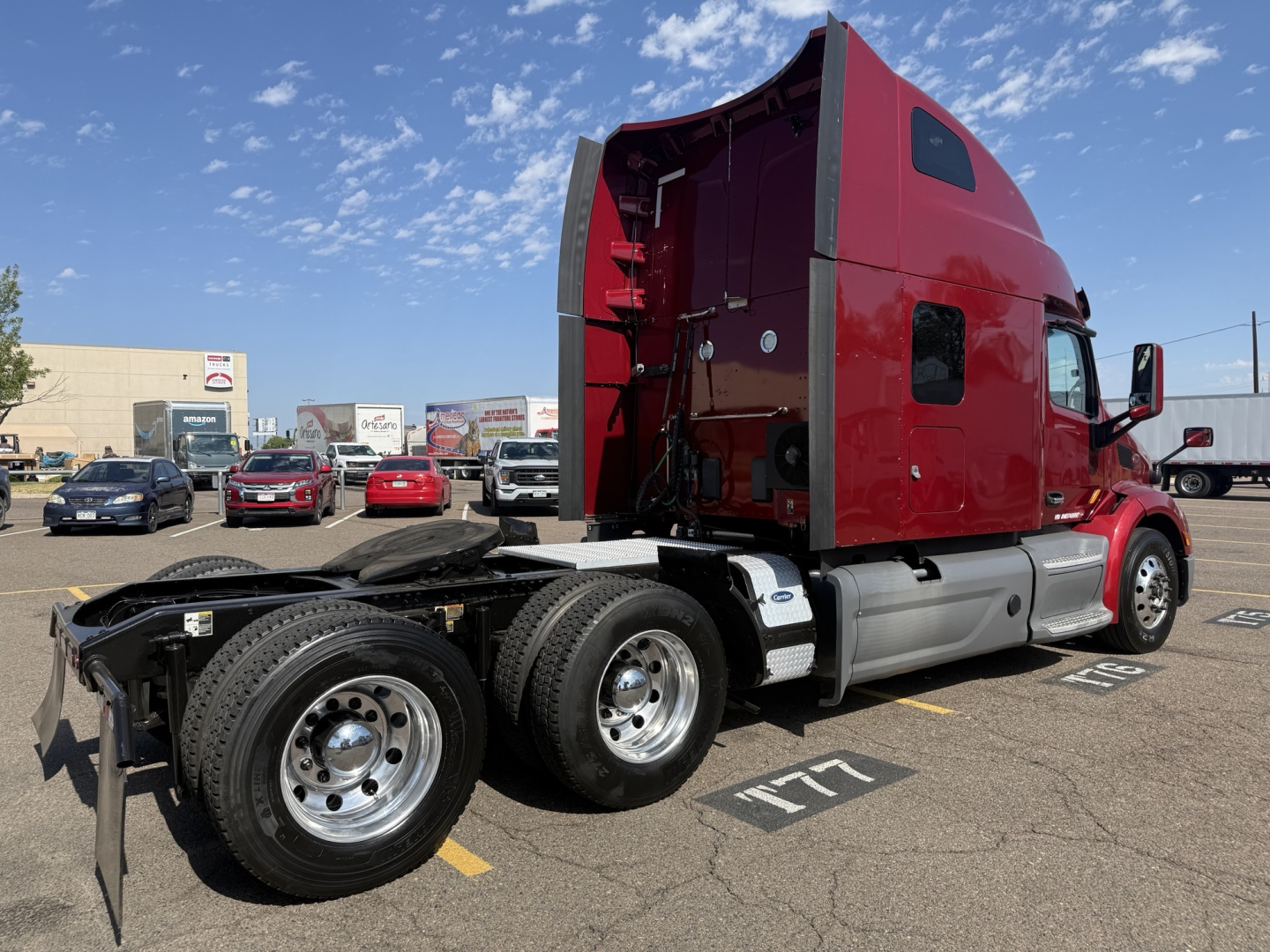 Peterbilt 579 tractor in red with open sleeper cab, side view showing rear wheel duals and chassis, no trailer attached.