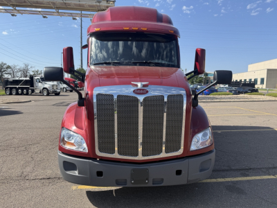 Peterbilt 579 front view showing large chrome grille and red cab with black mirrors.