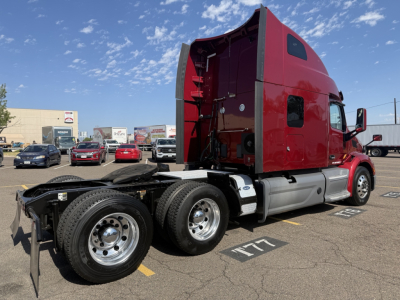 Peterbilt 579 tractor in red with open sleeper cab, side view showing rear wheel duals and chassis, no trailer attached.