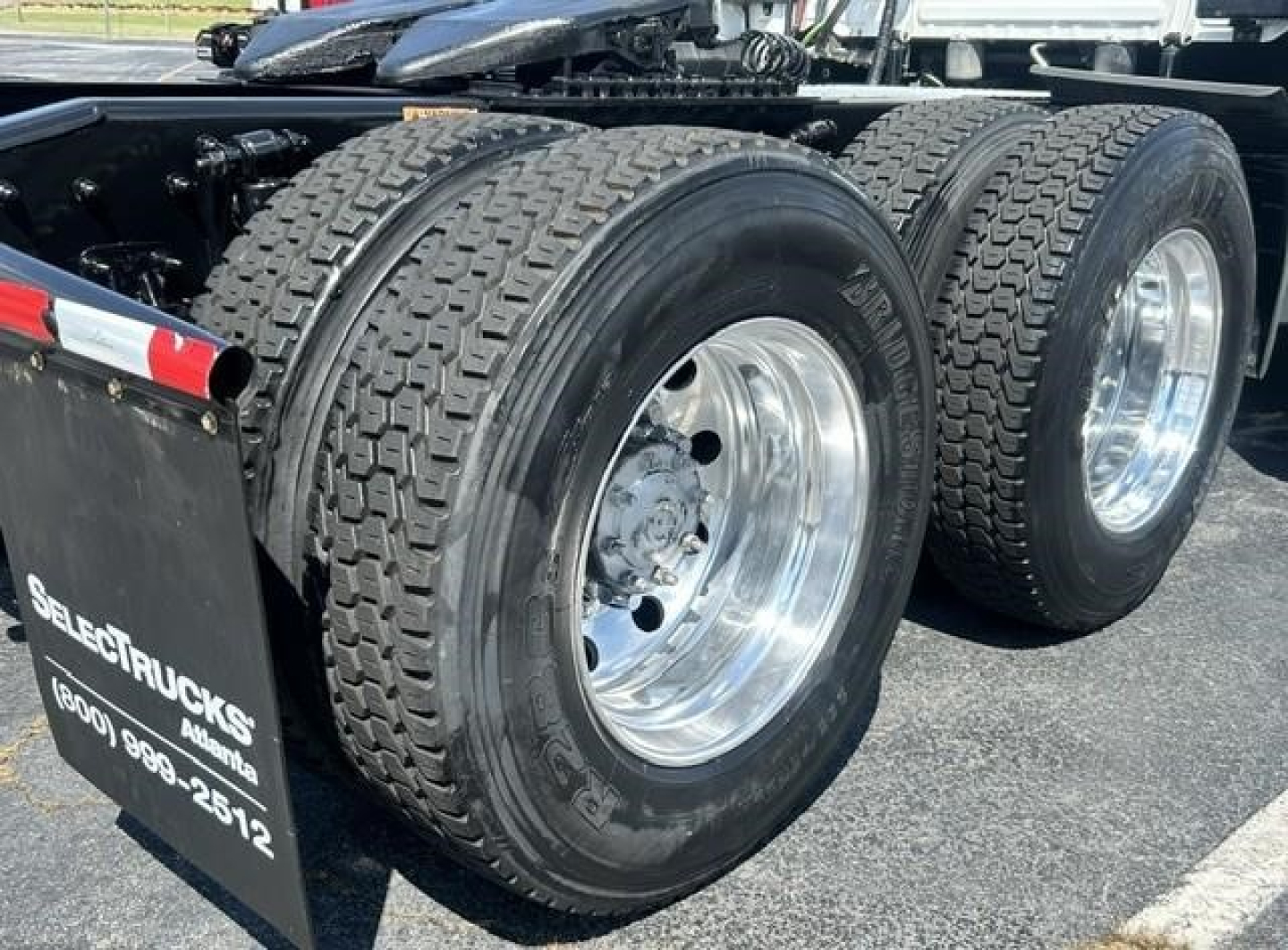 Freightliner Cascadia 126 axle area showing dual rear tires on polished aluminum rims and part of the chassis.