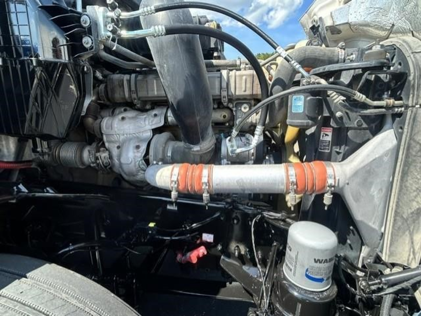 Freightliner Cascadia engine bay showing coolant hoses, air intake, and cylindrical filter canister labeled with NAVAR filter.