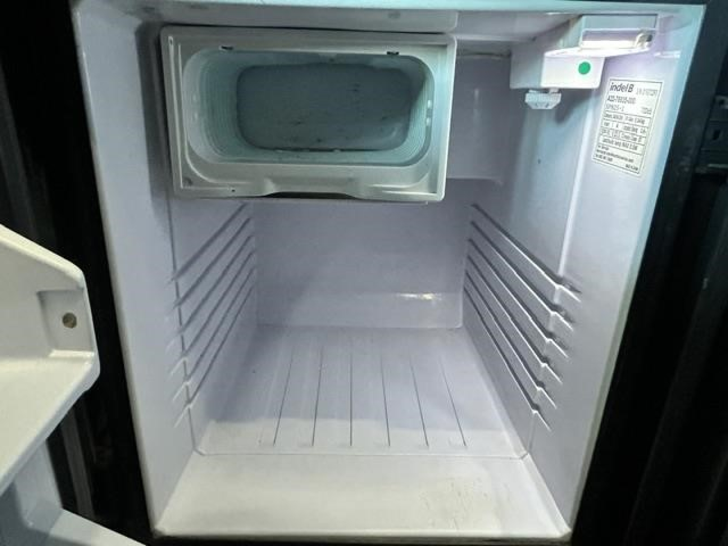 Fridge/freezer inside Freightliner Cascadia cab showing open compartment with icebox and clean interior.