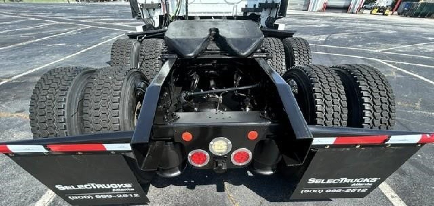 Rear view of a Freightliner Cascadia truck showing dual rear axle and fifth-wheel undercarriage with multiple tires and mud flaps. Visible lights and bumper area.