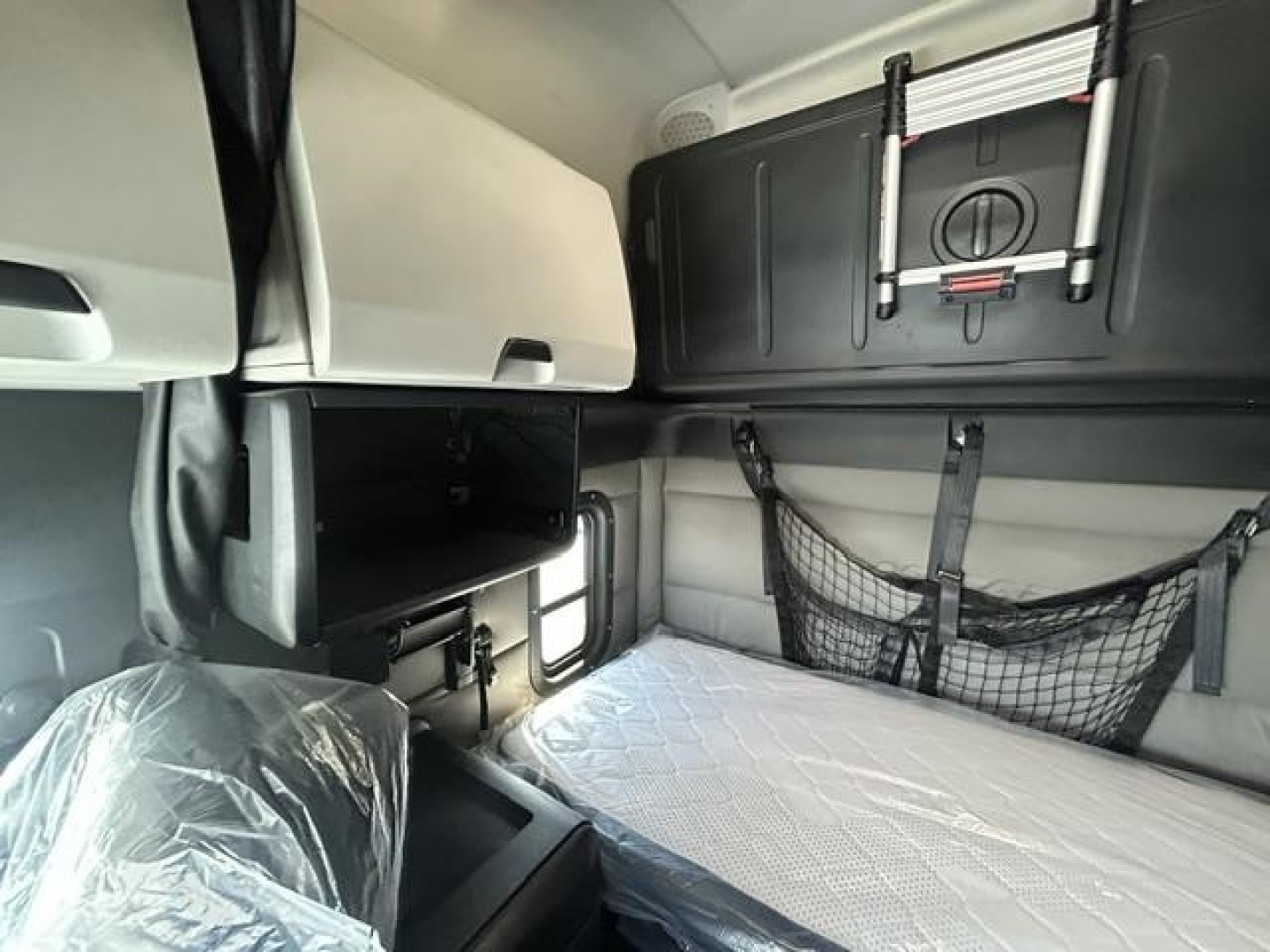 Truck sleeper cab interior with storage compartments and a padded bed area in a Freightliner Cascadia 126.