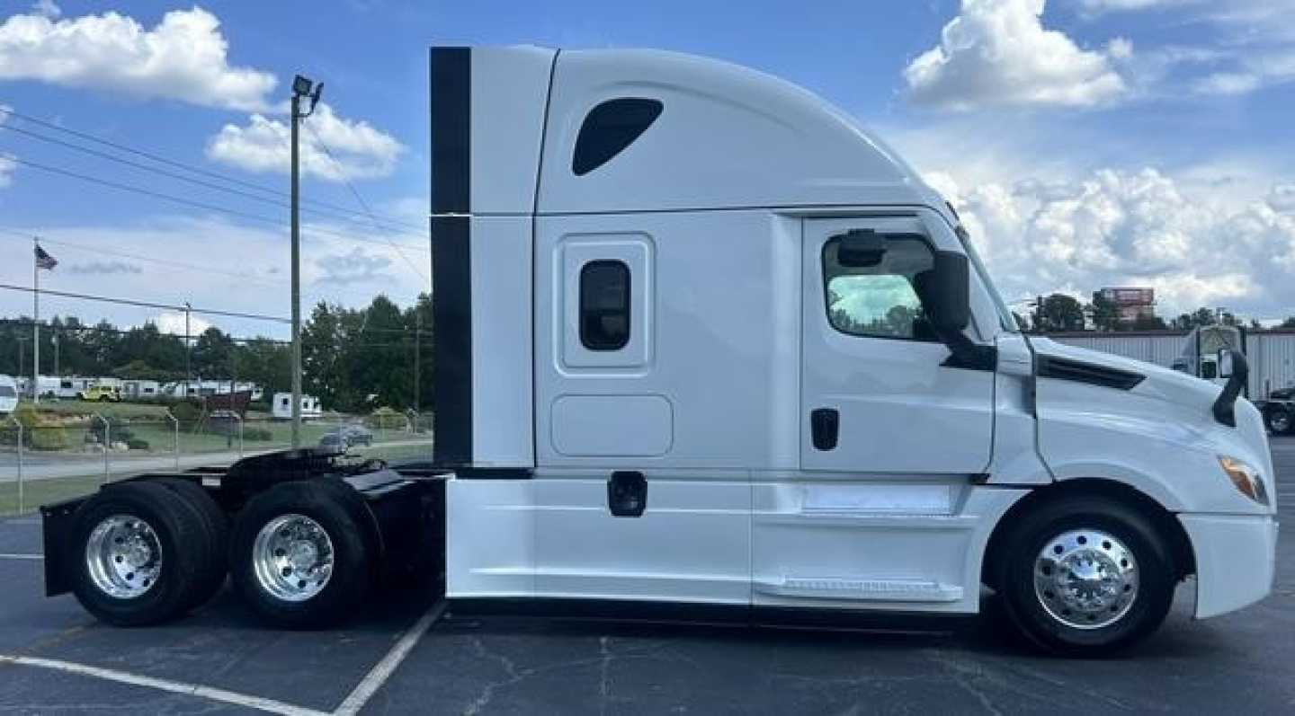 Truck side view of a 2021 Freightliner Cascadia 126 sleeper cab showing highway wheels and chrome rims.