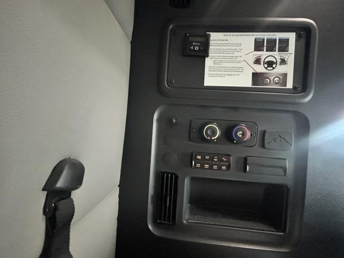Cab interior showing control panel with knobs and storage, in a Freightliner Cascadia sleeper truck cabin.
