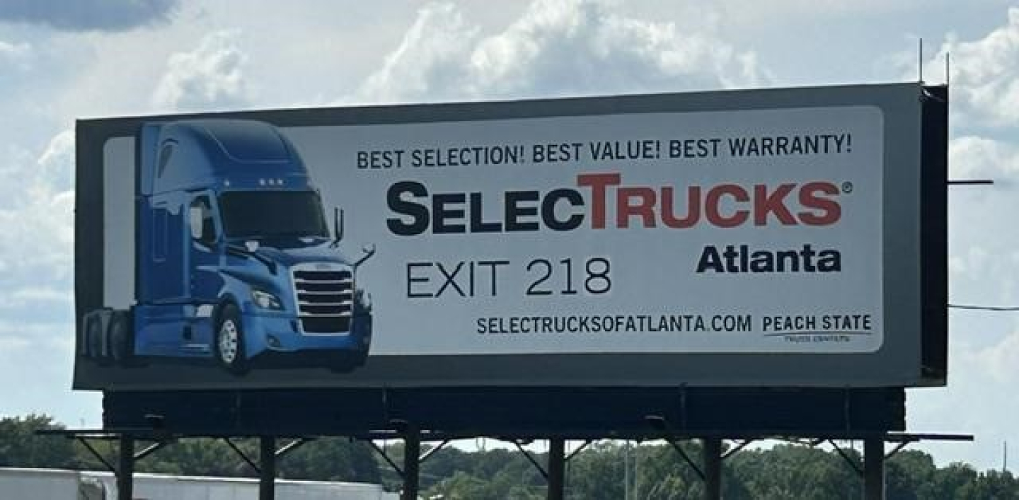 Billboard showing SelectTrucks Atlanta exit 218 with Freightliner image and slogan Best Selection Best Value Best Warranty.