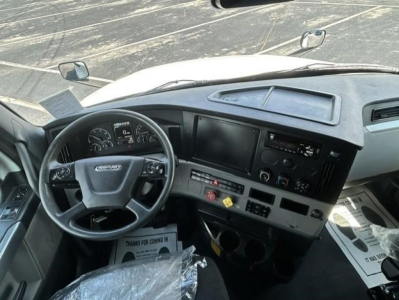 Cab dashboard and steering wheel of a Freightliner Cascadia 126 truck interior showing gauges, steering wheel, central console, and dash layout.