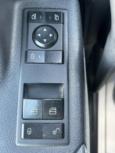 Truck interior control panel with window lock and mirror adjustment switches on left door of a 2021 Freightliner Cascadia 126.