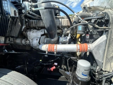 Freightliner Cascadia engine bay showing coolant hoses, air intake, and cylindrical filter canister labeled with NAVAR filter.