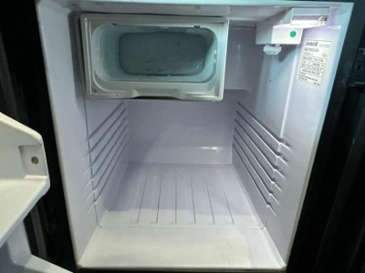 Fridge/freezer inside Freightliner Cascadia cab showing open compartment with icebox and clean interior.