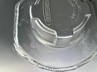 View of fuel tank cap on Freightliner Cascadia 126 showing cap with warning text and tether.
