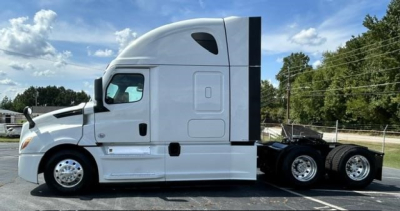 Freightliner Cascadia 126 side view showing sleeper cab, white exterior, dual rear axles, and chrome wheels.
