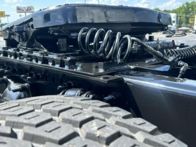 Freightliner Cascadia truck chassis showing suspension springs and air lines with visible rear wheel and frame components.