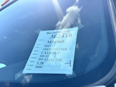 Vehicle window sticker visible on the dashboard showing 2023 Freightliner Cascadia DD-15 DT-12 (AUTO) 2.28 MHC, CA126SLP, stock 362410, VIN MJ6965.