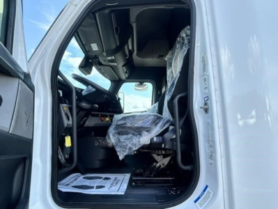 Freightliner Cascadia 126 truck cab interior view showing driver's seat with plastic cover, steering wheel, dashboard, and entry door frame.