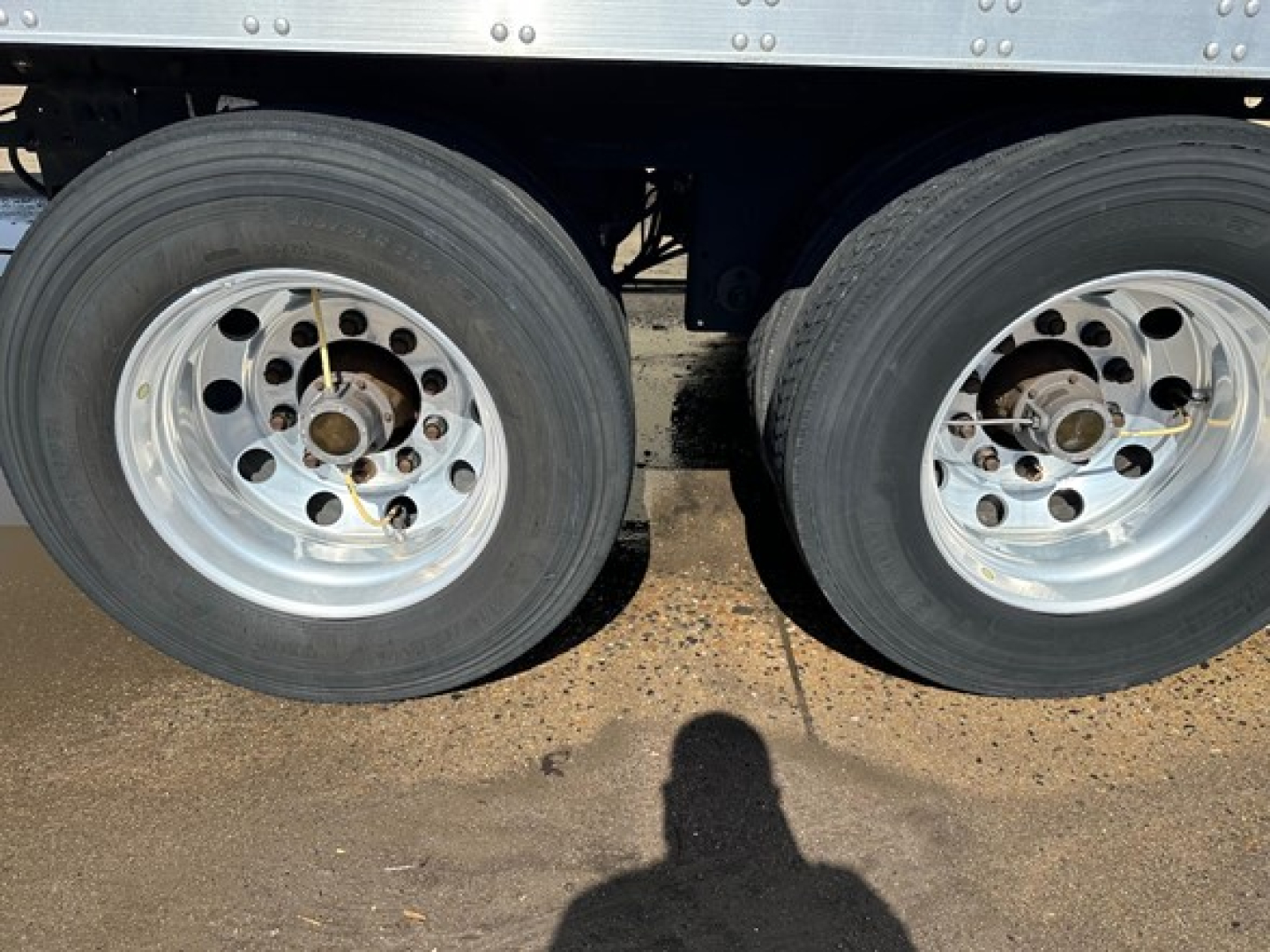 Rear twin axle of a 2021 Utility 3000R trailer showing dual wheels with aluminum rims and tires.