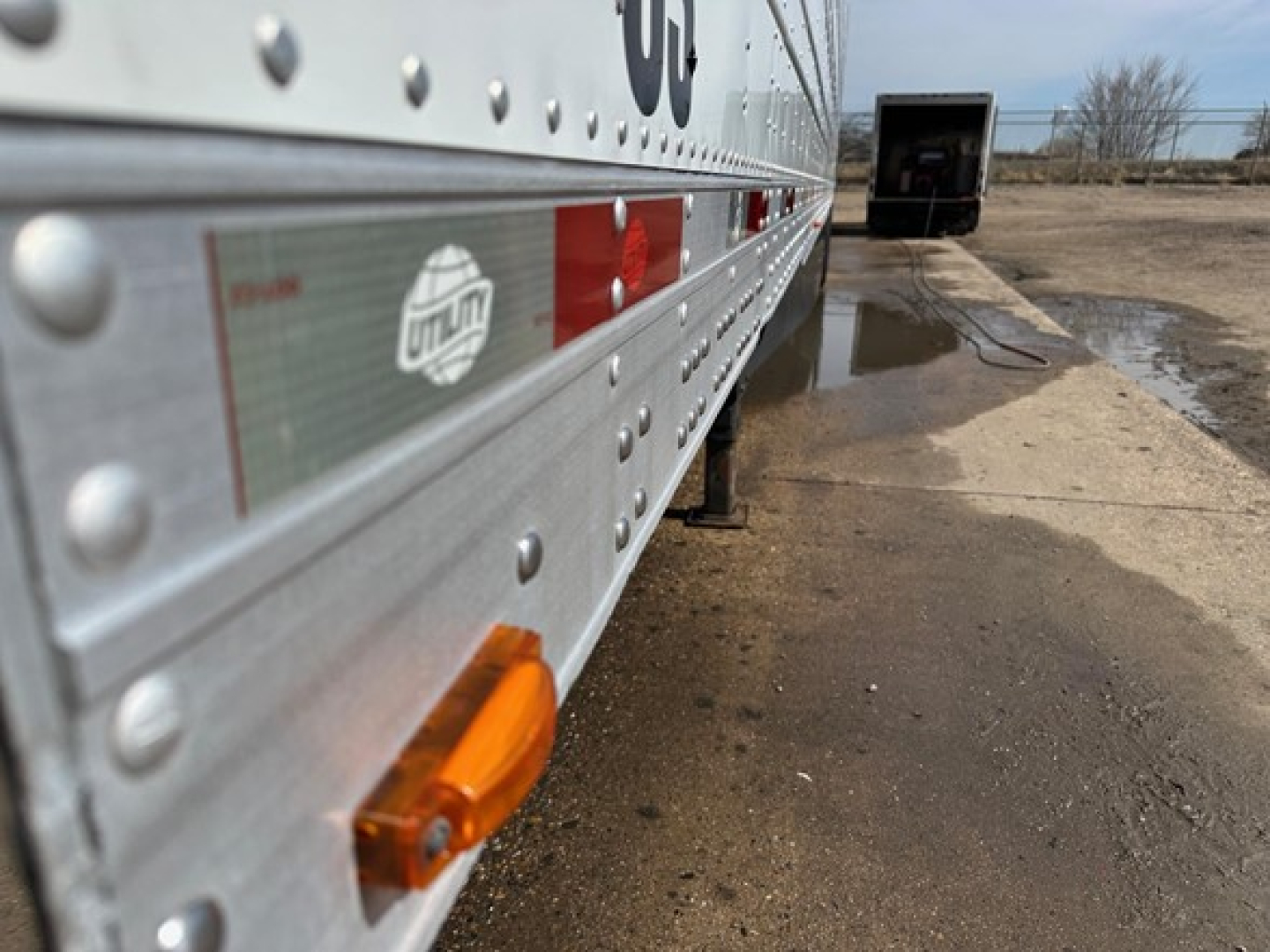 Trailer side of a 2021 Utility 3000R reefer showing riveted aluminum wall and an orange side marker light.