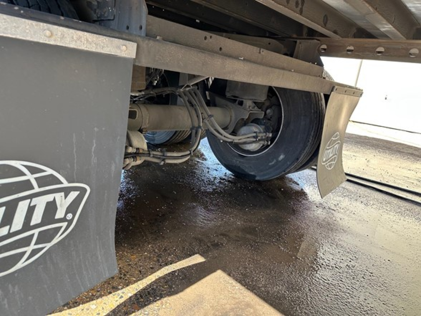 Trailer undercarriage showing rear suspension, axle, and mudflap with City logo and pipework visible.