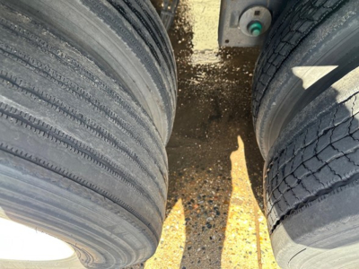 Two heavy-duty trailer tires with a glimpse of the trailer's undercarriage; no legible labels or text visible.