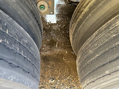 Truck trailer wheels showing worn tires and mud on ground between dual axles of a used 2021 Utility 3000R trailer.