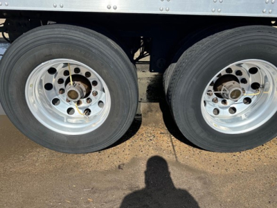 Rear twin axle of a 2021 Utility 3000R trailer showing dual wheels with aluminum rims and tires.