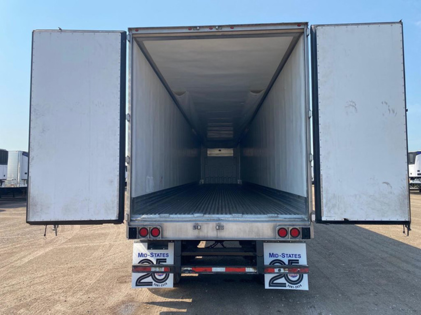 Trailer rear view with open refrigerated cargo area, empty interior, tail lights, and mud flaps. Doors open wide showing empty box.