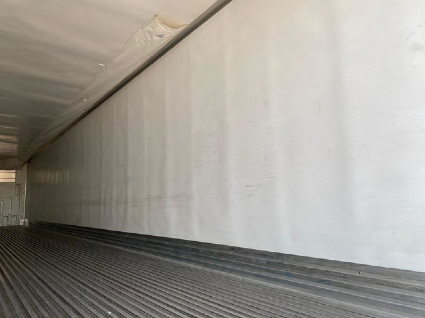 Trailer interior showing aluminum side walls and ribbed floor of a refrigerated trailer.