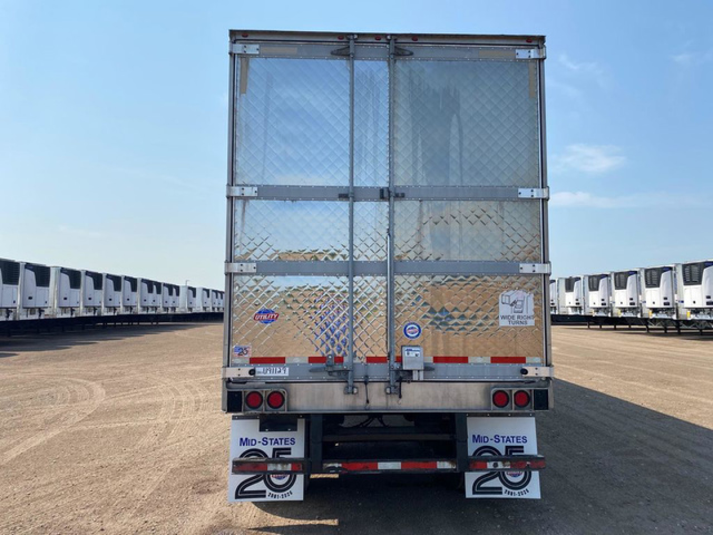 Rear view of a 2021 Utility Reefer trailer showing metal mesh doors, diamond plate surface, taillights, and bumper with signage.