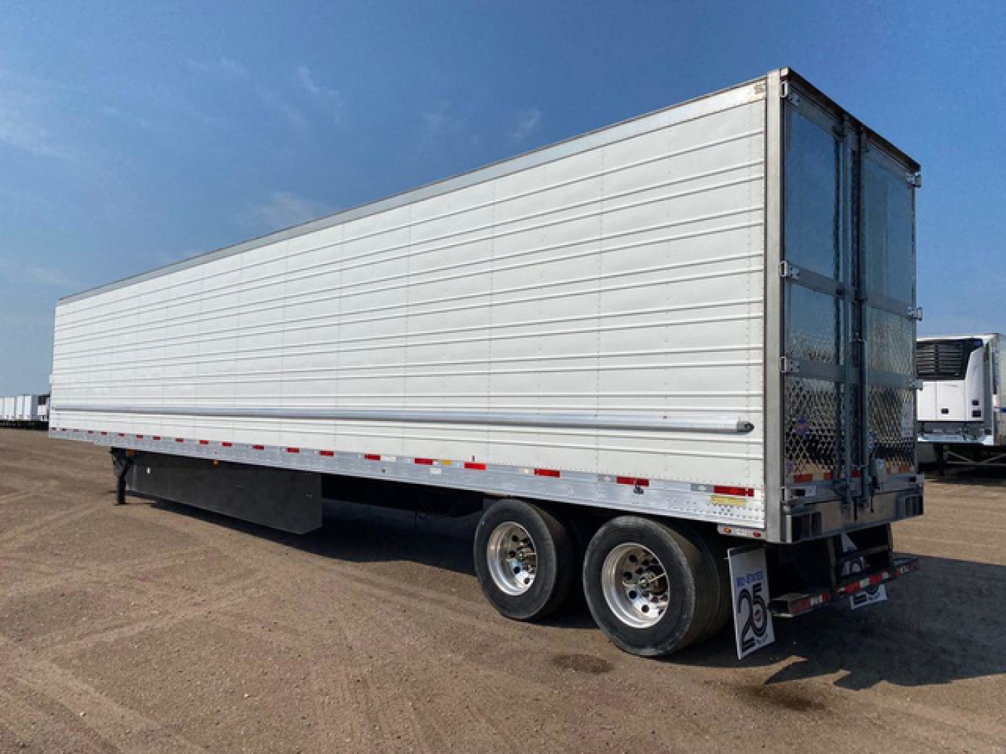 Utility refrigerated trailer in side view showing aluminum walls, tandem axles, and rear doors with metal frame.