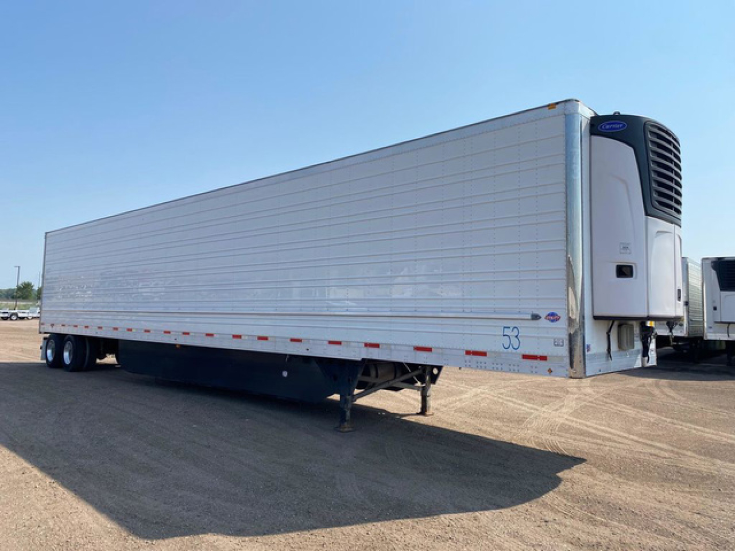 Trailer side view of a 2021 Utility reefer trailer with a refrigerated unit at the front, aluminum paneling, and dual rear wheels.