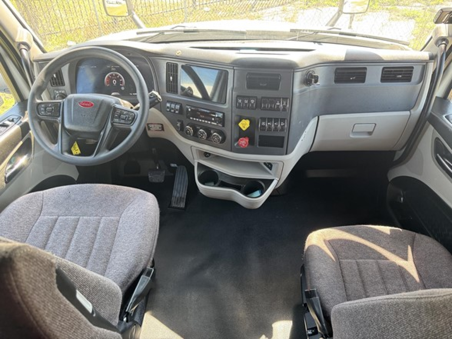 Peterbilt 579 cab interior showing steering wheel, dashboard with gauges, center console, and seating in driver's area.