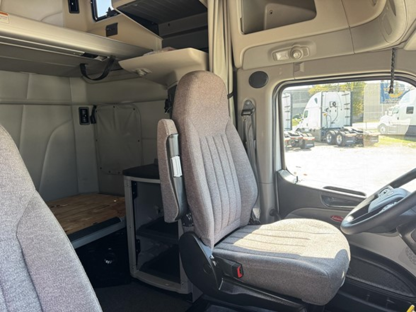 Peterbilt 579 truck cab interior showing driver seat and sleeper area with overhead storage and work surface.