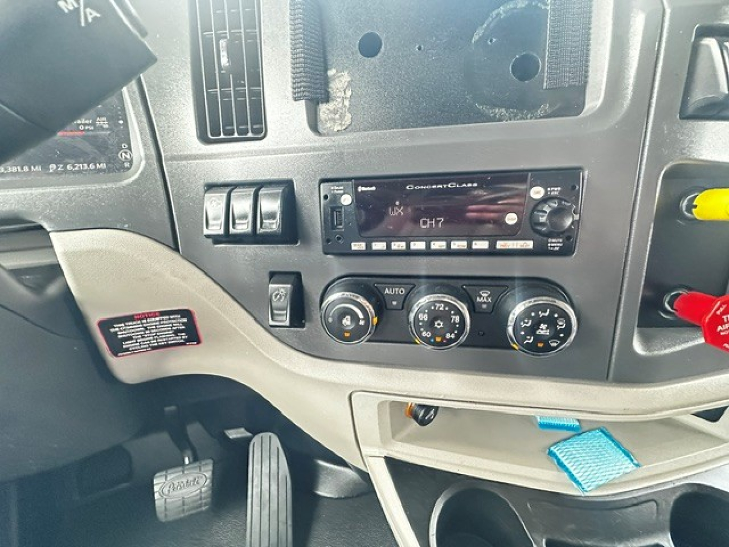 Peterbilt 579 truck cabin dash showing factory radio and climate controls with CH7 display, various gauges, and a blue tag visible.