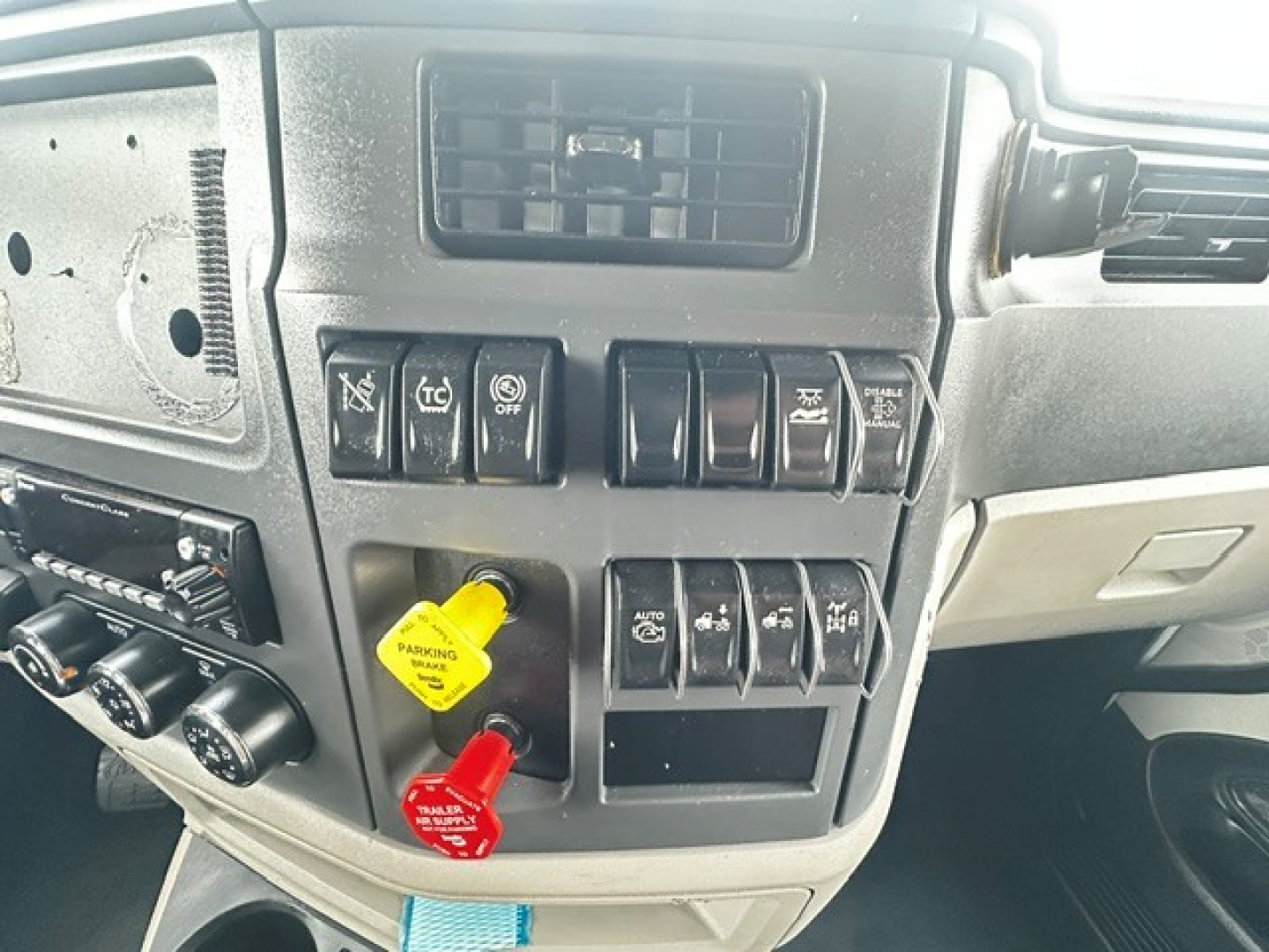 Peterbilt 579 dashboard with control switches and ignition keys area showing yellow and red switch handles.