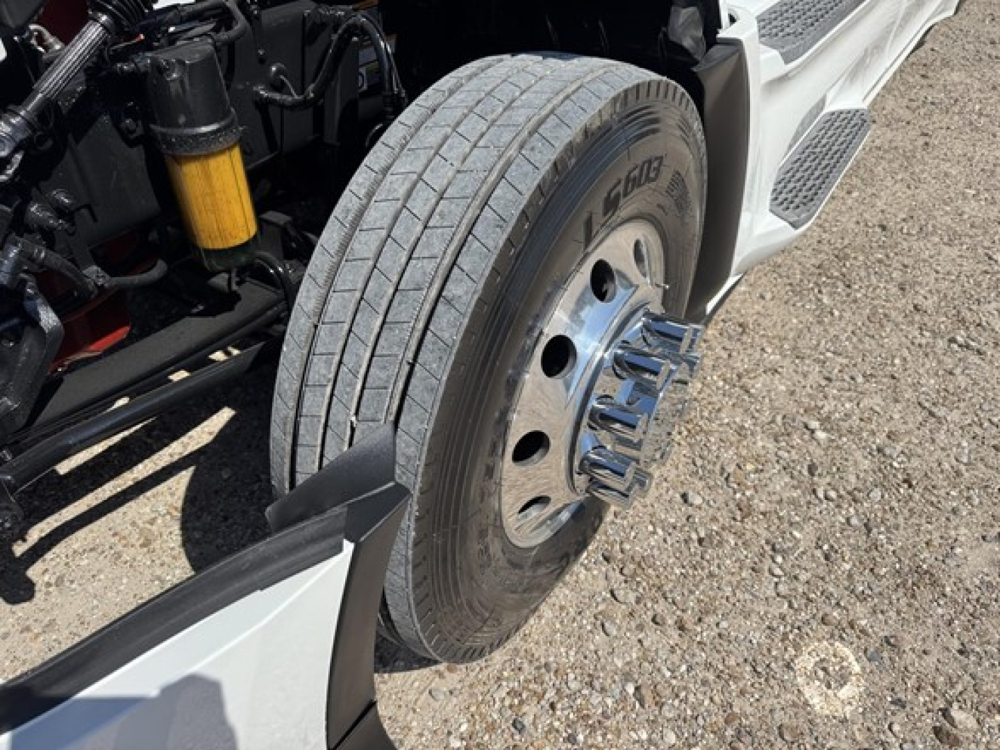 Peterbilt 579 front wheel assembly with tire, part of the highway tractor’s front left side showing suspension and chrome wheel lug nuts.