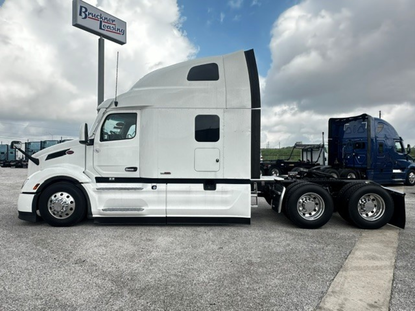 Peterbilt 579 sleeper cab truck side view showing a white exterior and dual rear axles.